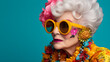 Portrait of gray haired senior lady with bright make-up in colorful bright clothes and sunglasses posing on blue background isolated with copy space. The concept of beautiful aging, outrage, self-expr