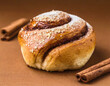 Freshly baked cinnamon bun on a brown background.