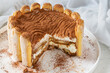 Tiramisu cake with a rim of ladyfingers or savoiard biscuits an white background.