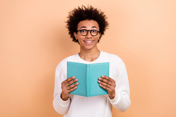 Poster - Photo of cheerful smart man wear trendy white clothes hold encyclopedia fiction science genre book isolated on beige color background