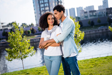 Wall Mural - Portrait of joyful family smiling couple young beautiful lovers hugs outdoors spending time together on local river and city background