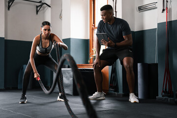 A man and a woman are building leg muscles with ropes in a gym