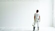 A painter clad in white, splattered with paint, pauses to view a freshly painted wall in a bright, airy space.Painter's Pause