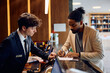 © Drazen - Black man signing documents while checking in at hotel.