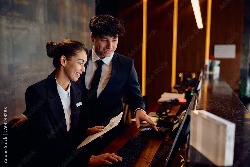Hotel Receptionist Job Using Computer Happy receptionists cooperating while working on computer at hotel ...