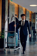 © Drazen - Full length of happy bellhop at hotel lobby looking away.