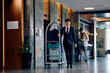 © Drazen - Hotel attendant pushing luggage cart in a lobby and looking at camera.