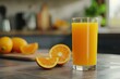 A glass of freshly squeezed orange juice adorned with a slice on the rim, situated on a kitchen counter with blurred background for a homely feel