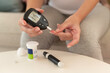 Close up of woman checking blood sugar level by using Digital Glucose meter, health care, medicine, diabetes, glycemia concept