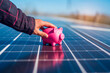 Man hand next to solar panels with a pink piggy bank on them, suggesting savings when using solar panels
