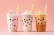 A few different tastes milktea with cute faces and straws. Bubble tea. Peach color background.