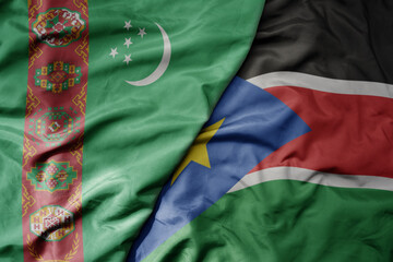 big waving national colorful flag of south sudan and national flag of turkmenistan.