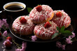 Donuts with pink icing and strawberries on top on a black plate, flowers on the background