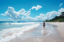 A Woman Walking Along The Sandy Beach Next To The Vast Expanse Of The Ocean On A Sunny Day, Surfer Girl Paddling Out To The Waves With Long, White Sandy Beach As Backdrop, AI Generated