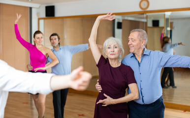 Wall Mural - Happy older couple performing a paired ballroom dance in ballroom