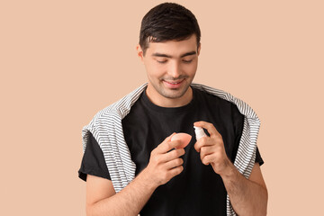 Wall Mural - Male makeup artist with foundation and sponge on beige background