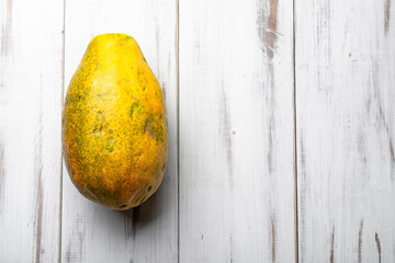 Poster - A ripe yellow fruit with a brown spot sits on a wooden table