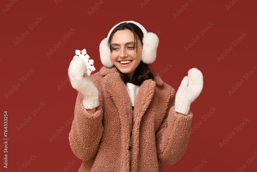 Happy young woman with decorative snowflakes on red background