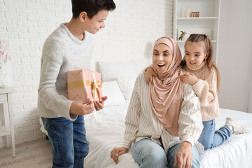 Poster - Little children greeting their Muslim mother with gifts in bedroom