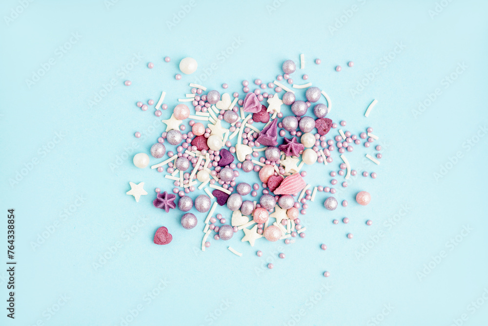 Sweet colorful sprinkles scattered on blue background