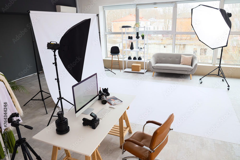 Interior of modern studio with photographer's workplace and professional equipment