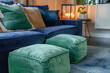 Emerald green poufs by a plush dark blue sofa, tranquil setting.