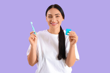 Wall Mural - Beautiful young happy woman with dental floss and toothbrush on purple background