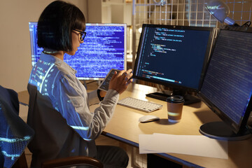 young female programmer working with tablet computer in office at night