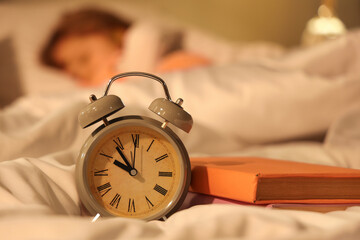 Wall Mural - Alarm clock and books on bed, closeup