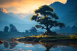 Old big tree in rural VietNam surrounded by misty lake in picturesque mountain valley at dawn
