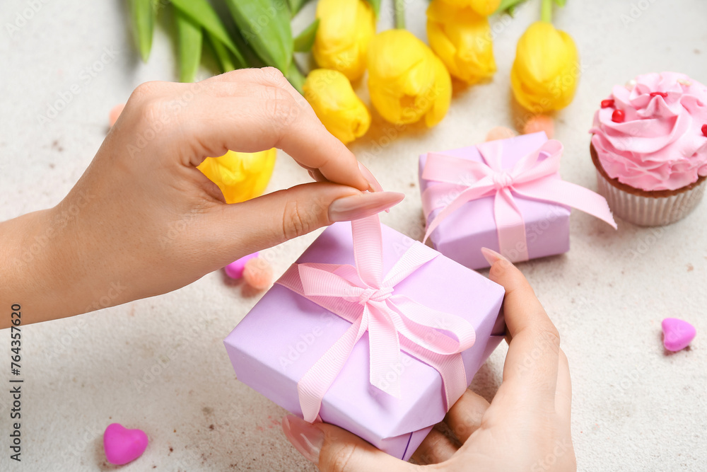 Female hands with amazing gift box on light background
