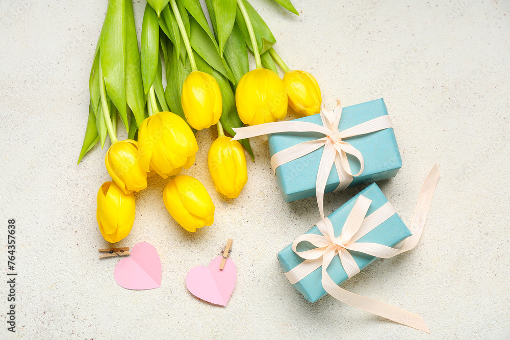 Yellow tulips, presents and paper hearts on light background