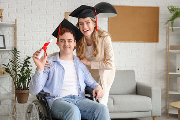 Canvas Print - Male graduate in wheelchair with diploma and his classmate at home