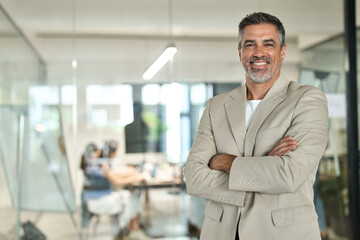 Portrait of confident happy rich middle aged business man investor, older team leader, mature professional company executive wearing suit standing arms crossed in office, chairman profile photo.