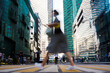 Woman in dress crossing downtown street with a long stride. Motion blur