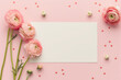 Feminine workspace desk. An empty white paper card note and fresh spring flowers on pastel pink background. Flat lay, top view.	