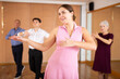 Smiling young attractive girl learning to dance kizomba, practicing moves solo in dancing class