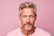 Portrait of mature man with grey hair and beard on pink background