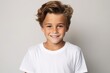 Portrait of a cute little boy in white t-shirt on grey background