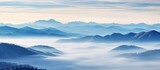 Fototapeta Na ścianę - A scenic view of misty mountains concealed in fog with low-lying clouds nestled in a serene valley