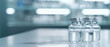Glass vials containing medical solutions and vaccines on a white table with blurred background. Medical background