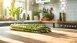 There is fresh and uncooked asparagus placed on a light wooden surface in the kitchen.