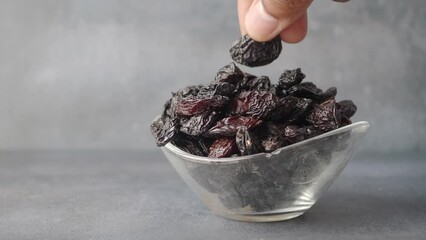 Poster - hand pick black raisin in bowl 