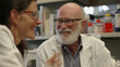 © sommersby - Elderly man with a white beard and glasses engaging in conversation with a woman in a lab coat