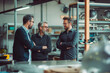 © BrightSpace - Three men are standing in a factory or warehouse, Serious discussion and talking to each other. They are all wearing glasses, discussing something important. Scene is serious and focused