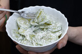 Fototapeta  - Jeśc plastry ogórka w śmietanie i przyprawach z bliska w salaterce