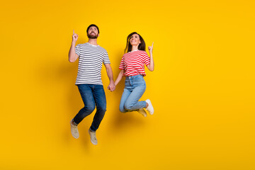 Sticker - Full size photo of cheerful couple dressed jeans look directing at proposition empty space isolated on vibrant yellow color background