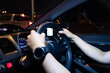 Male hands holding the steering wheel while driving a car at night