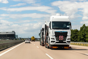 Wall Mural - Back view of semi-trailer flatbed vehicle deliverying many new electric trucks sale automotive dealer from factory plant on highway interstate road. New business cargo transport fleet export import