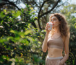 Beneath the leafy canopy, a woman enjoys her milkshake, surrounded by the rustling foliage and soft grass. Following her workout, the young lady in active wear